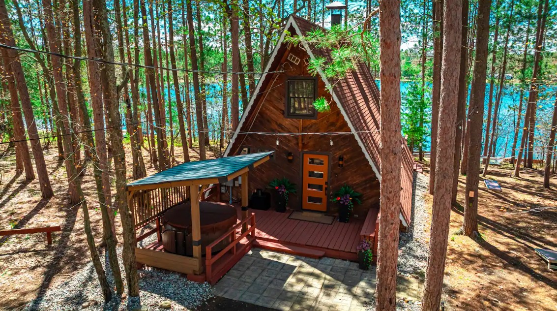 exterior of an a-frame cabin in the woods near the lake