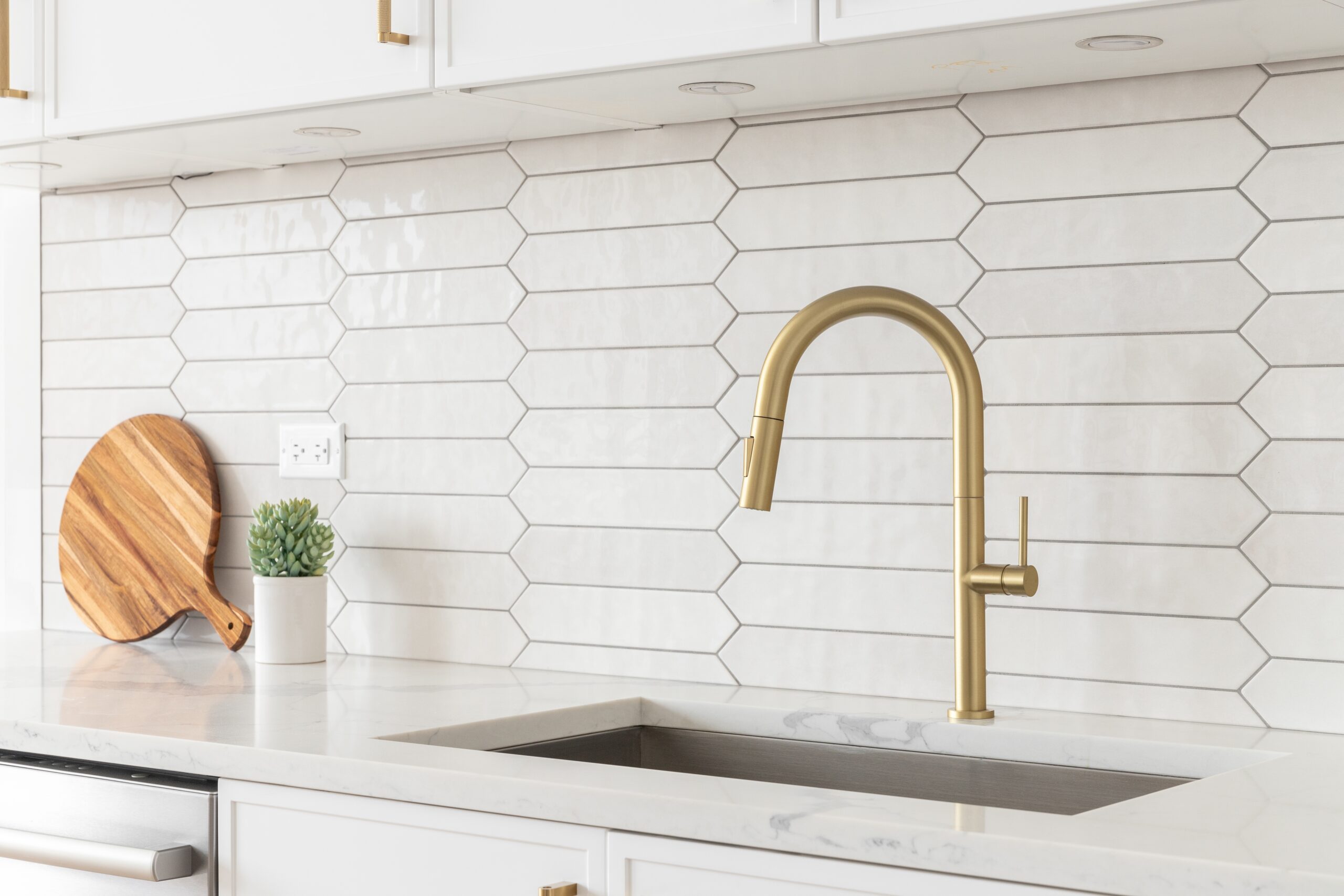 White kitchen backsplash with a gold faucet