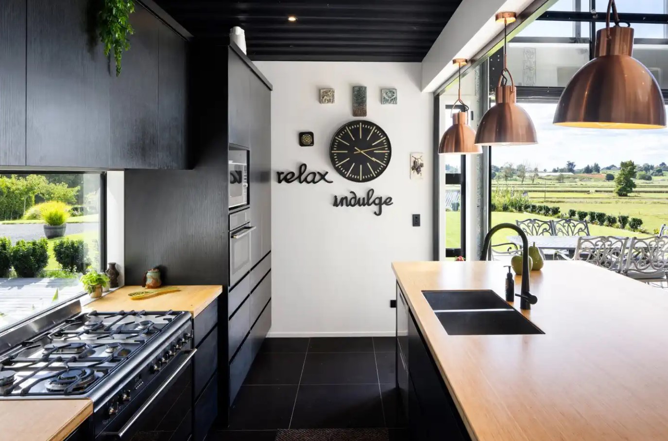 kitchen with wooden countertops, black cabinets, hanging lamps