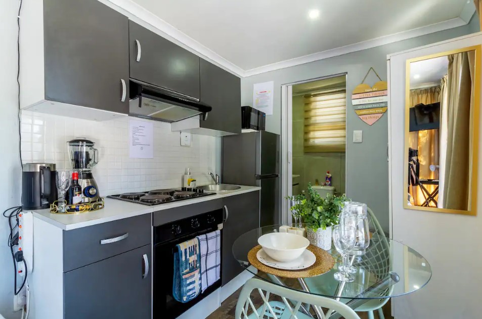 kitchen with gray cabinets, white countertop, round glass desk accompanied by two chairs