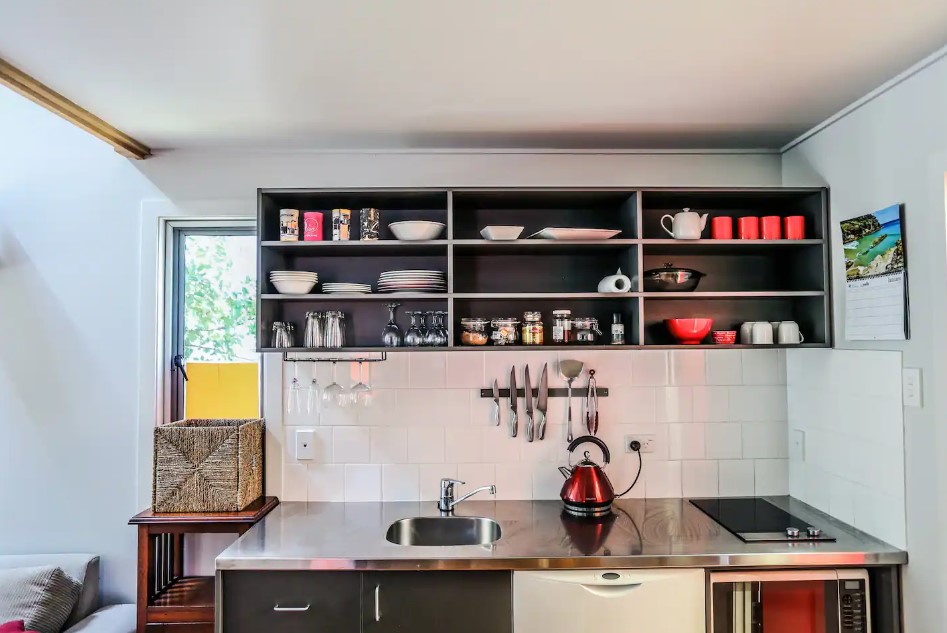 kitchen with white tiles, open cabinets above the silver countertop