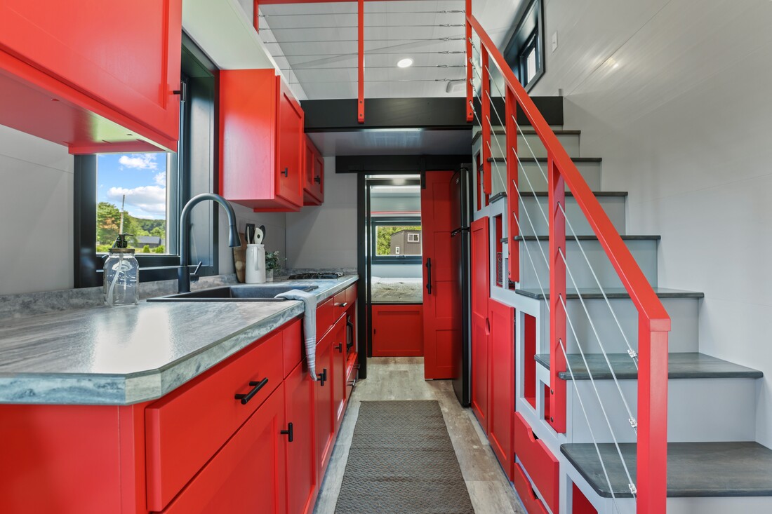 kitchen with red cabinets, red railing, white walls, gray countertop