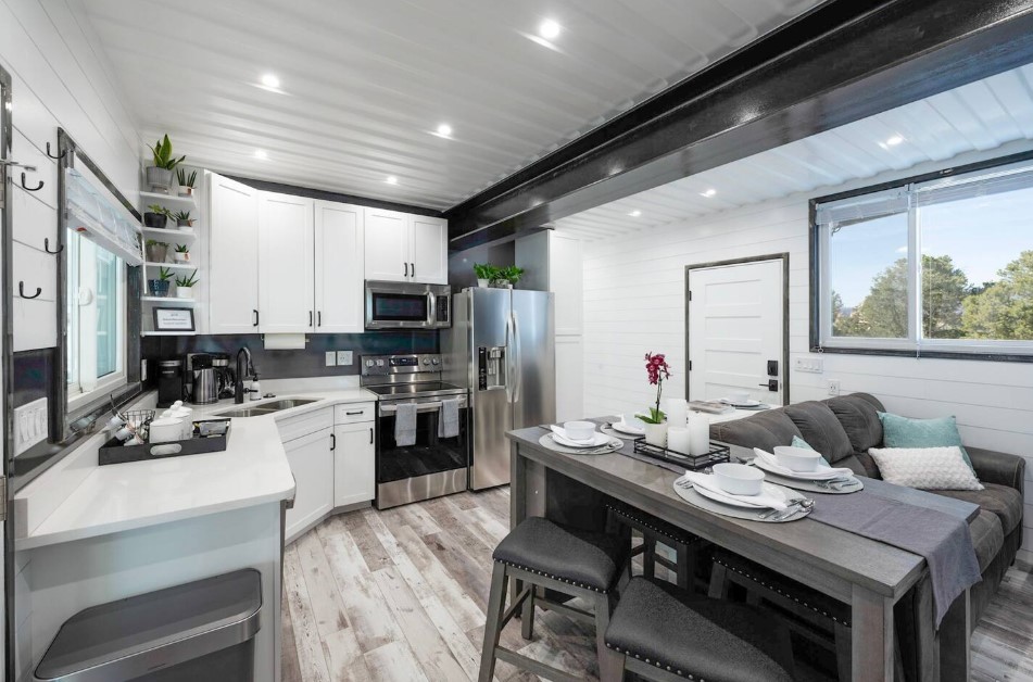 kitchen with white cabinets, dining table in brown gray color with four cushioned chairs and white walls