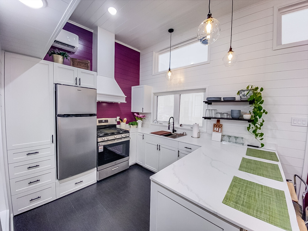 kitchen with white walls, one accented wall, white cabinets and marble countertops