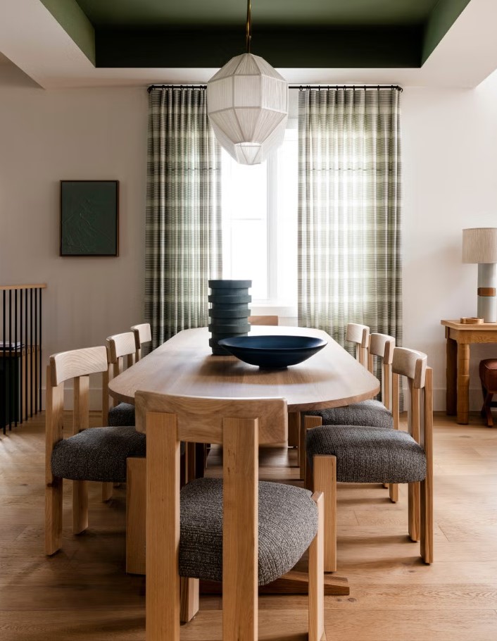 kitchen with an oval wooden tables accompanied by chairs and a dark green ceiling