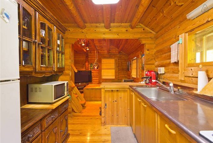 kitchen with wooden walls, brown wooden cabinets, microwave on the countertop, window above the countertop