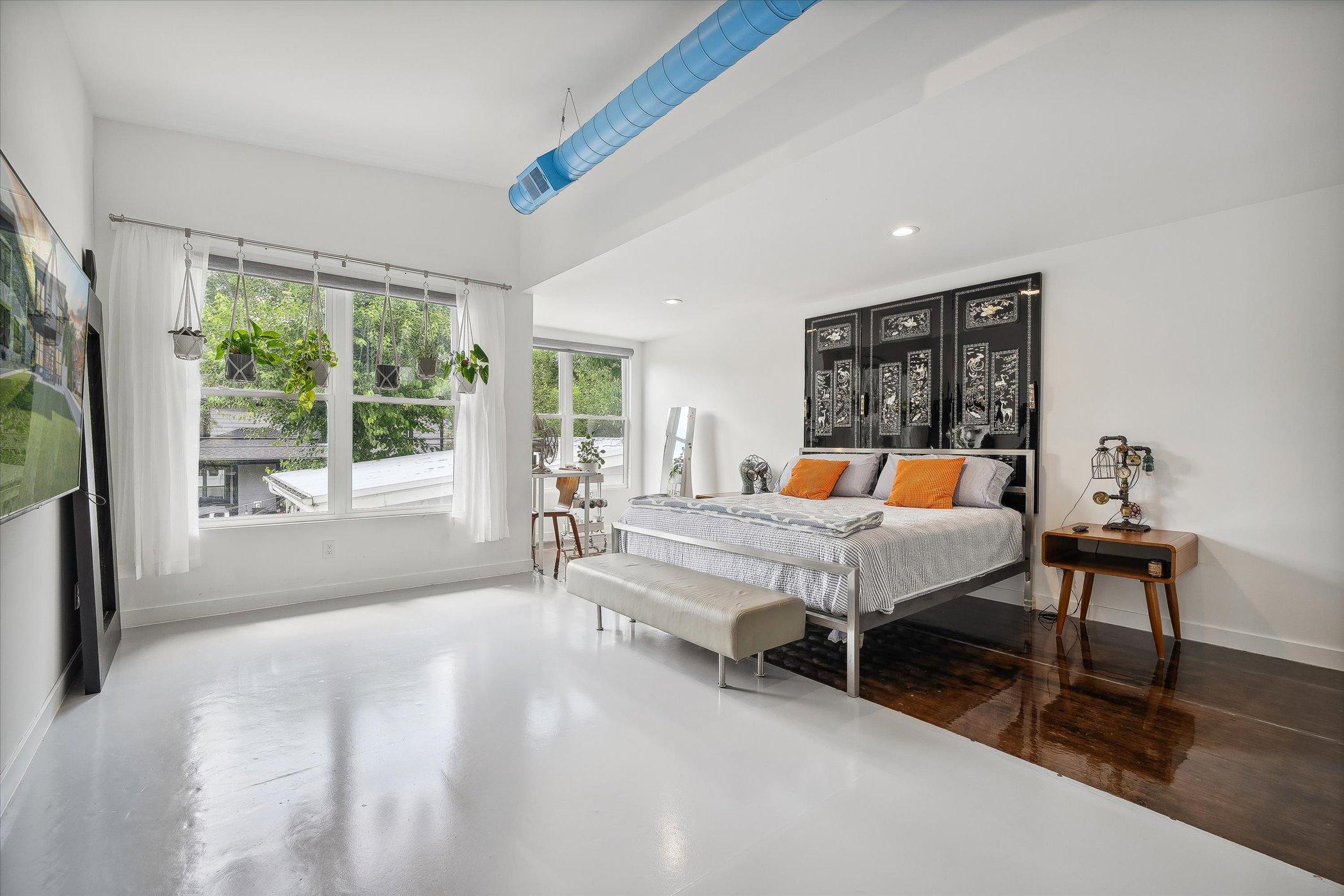 bedroom with a big bed, big windows, bedside tables, flat screen tv