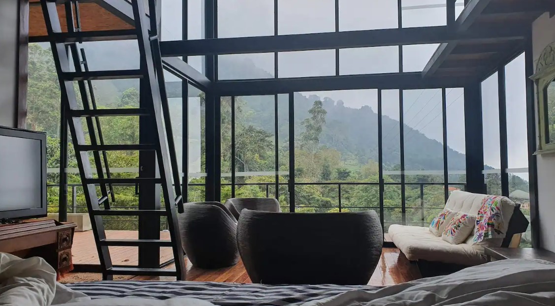 living room with floor to ceiling windows, round black chairs and an off-white couch