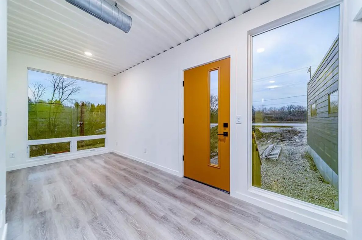 empty living room with white walls, floor to ceiling windows and orange brown doors