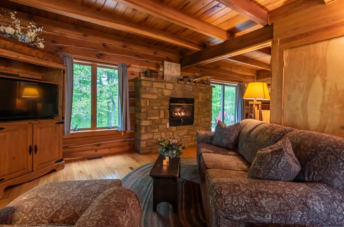 living room with a textured couch, tiny table, flat screen tv, wooden walls, fireplace