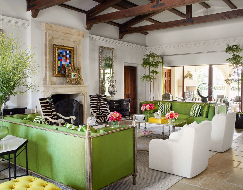 living room with white chairs, zebra chairs and green couches, glass table in the middle of the room, wooden beams on the ceiling