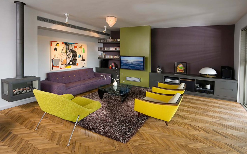 living room with purple, green and white walls, purple couch and yellow chairs and a fireplace