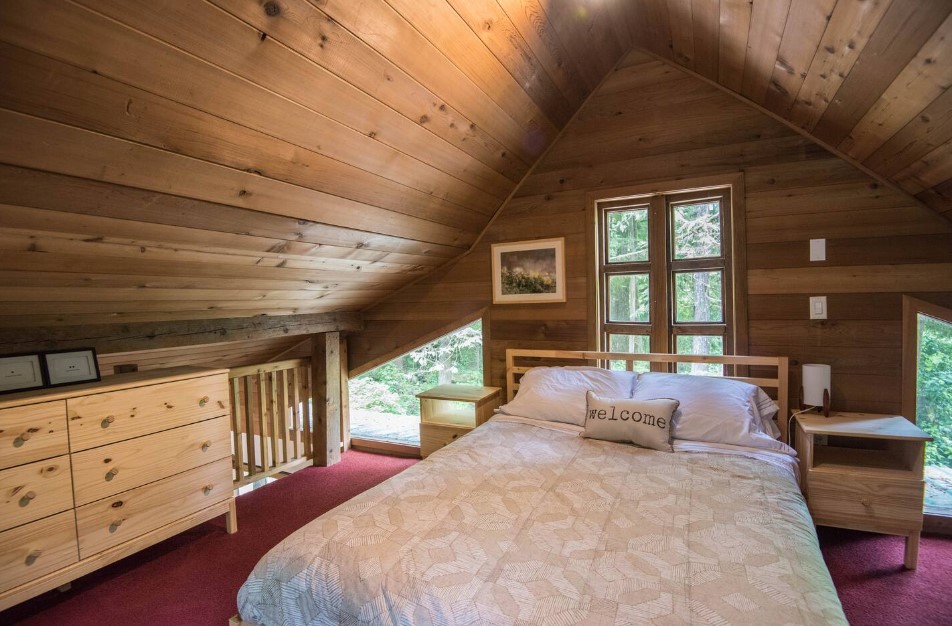 loft bedroom with a bed, bedside tables, windows, and a brown cabinet