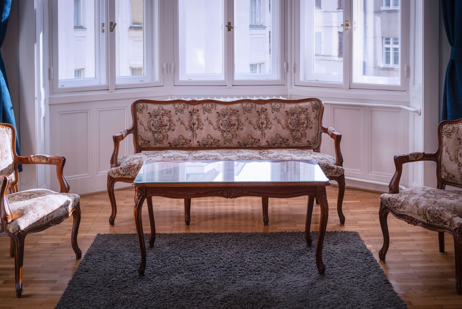 couch and two chairs with same patterns next to the wooden table with glass on top