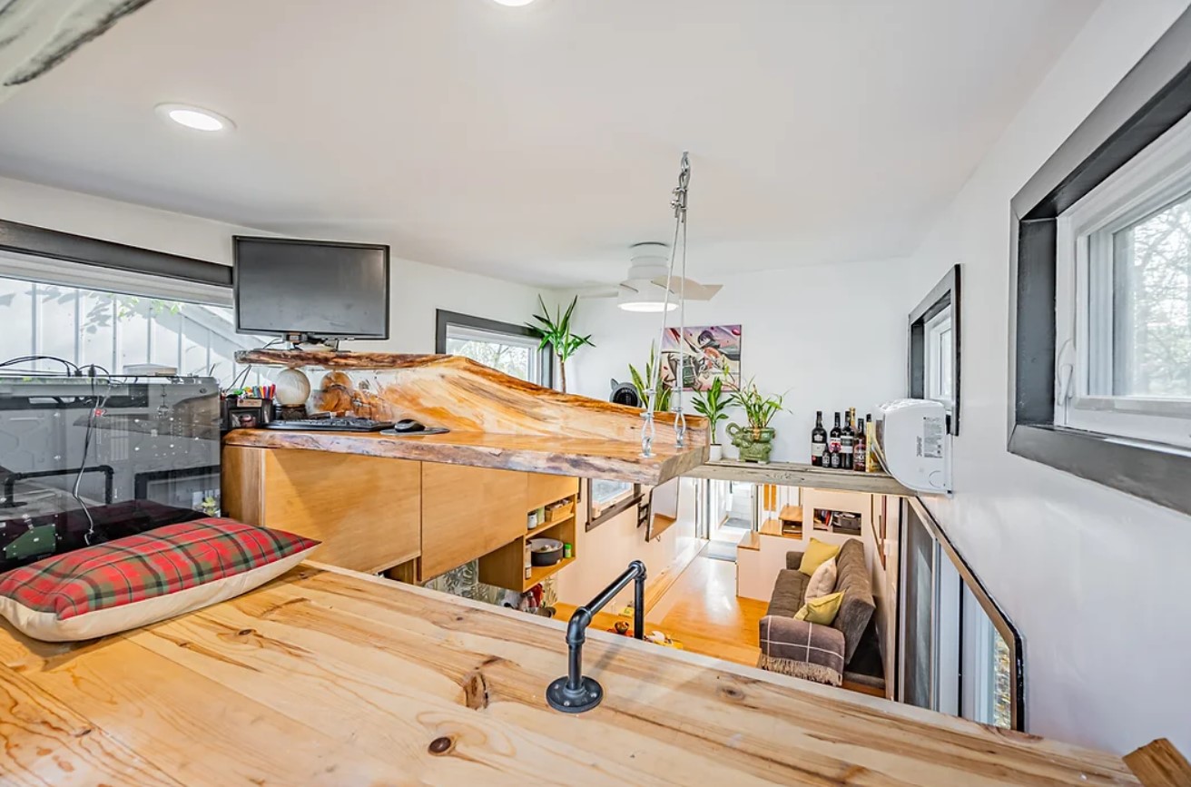 loft office area with a hanging wooden countertop and a computer on top