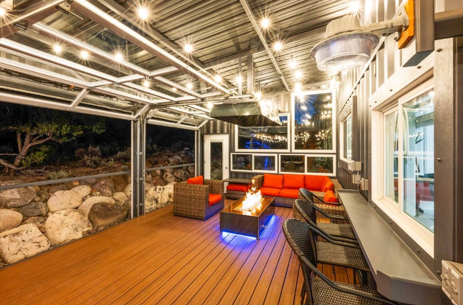 patio with a fire table, red cushioned sitting areas, a black bar with chairs