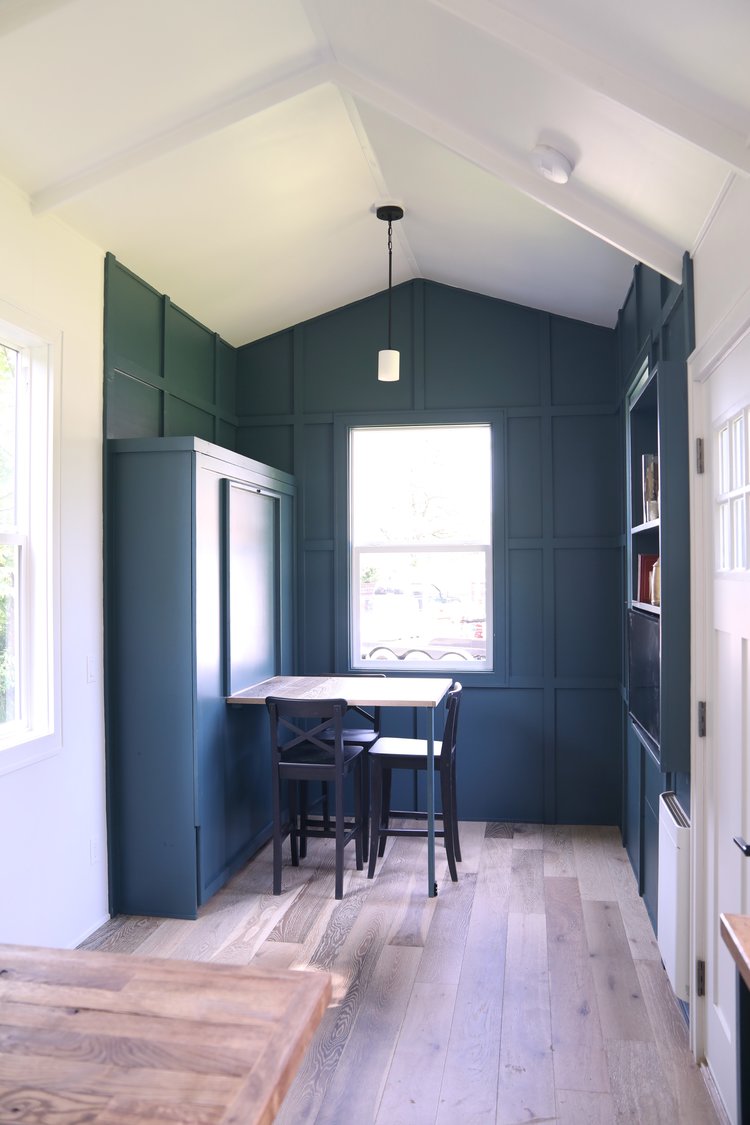 room with dark teal walls, foldable dining table with black chairs