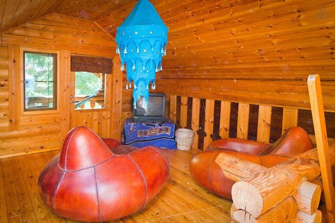 room with two brown leather sofa chairs, tiny tv, wooden walls