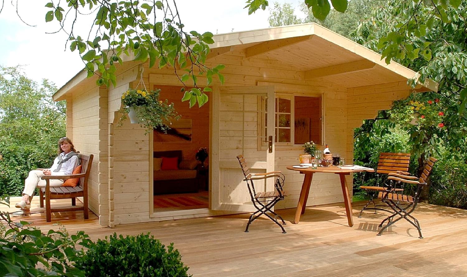 exterior of a tiny home with wooden walls and a small terrace with a tiny table accompanied by the chairs