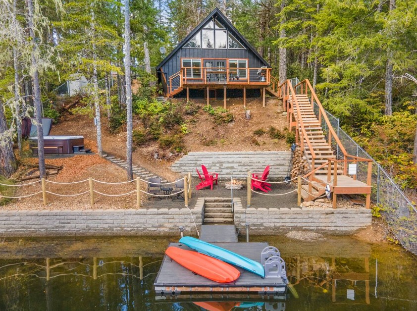 exterior of a cabin near the lake with a fire pit in front and a deck