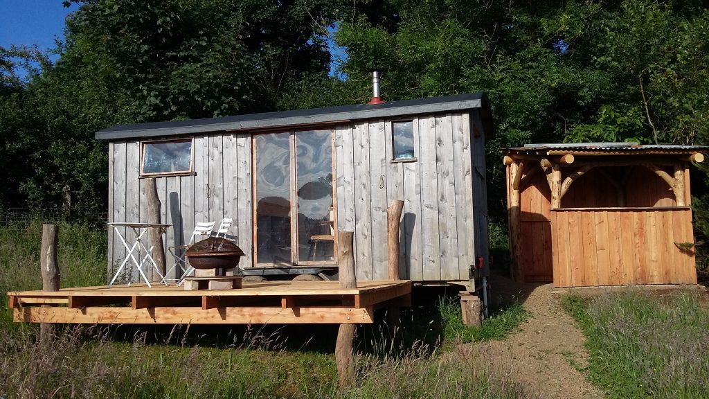 exterior of a tiny home with a little terrace in front with a round table and two chairs