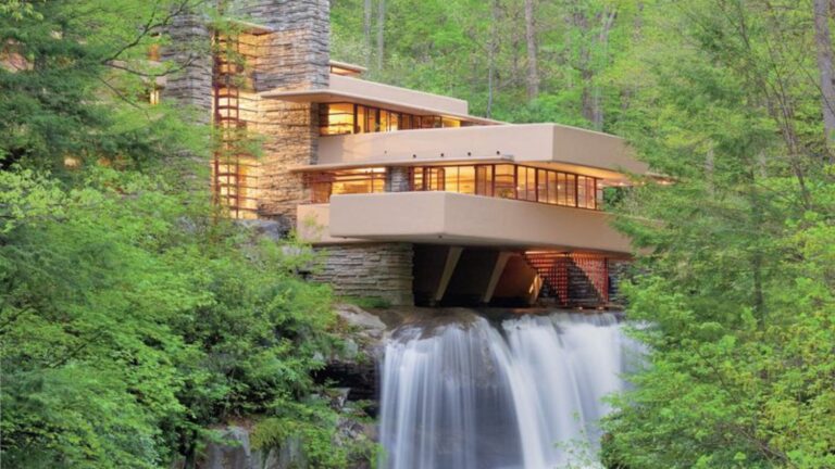 exterior of a home in surrounded by greenery on top of falling water