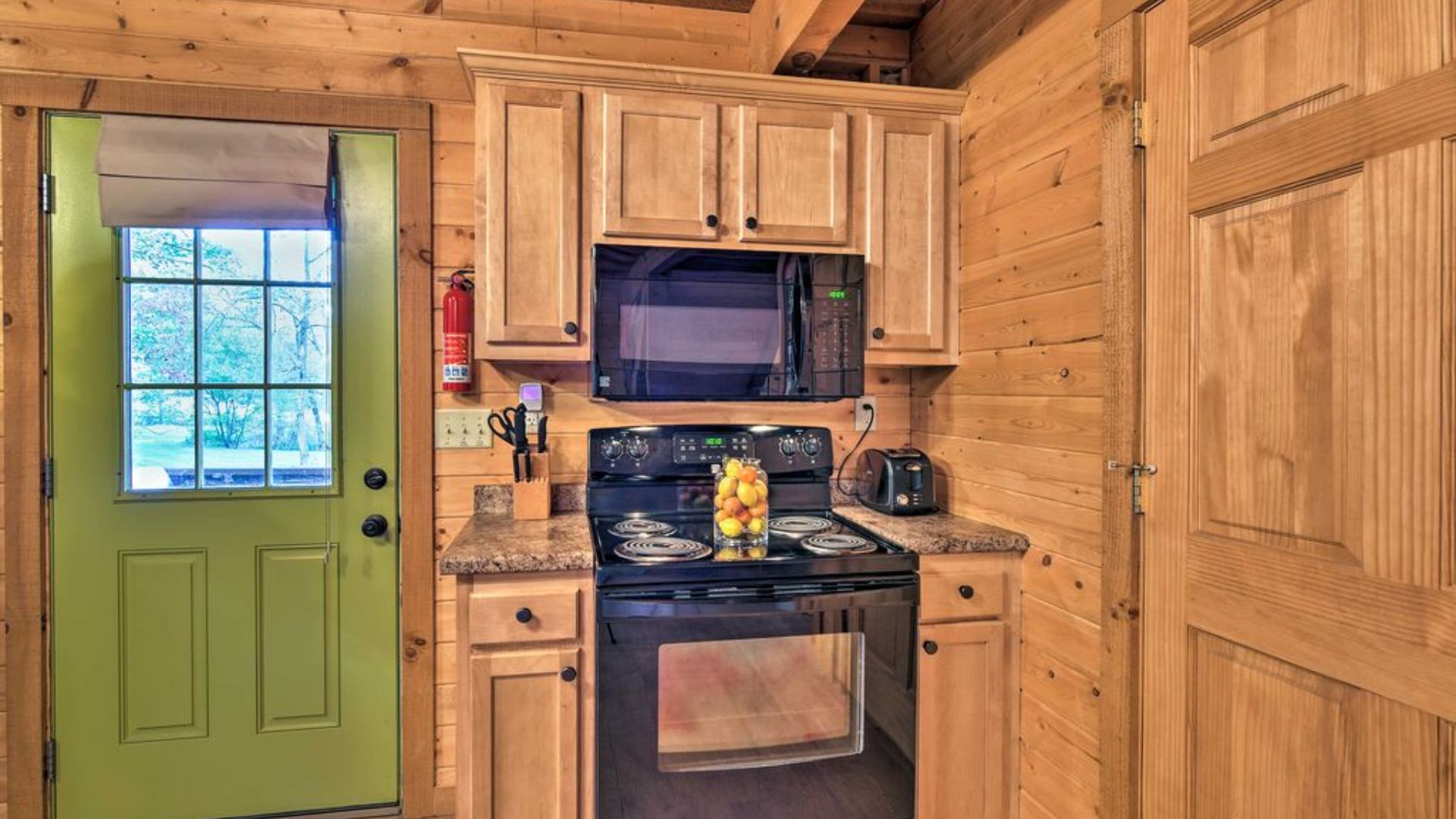 small cooking station with a stove and a microwave by the green door