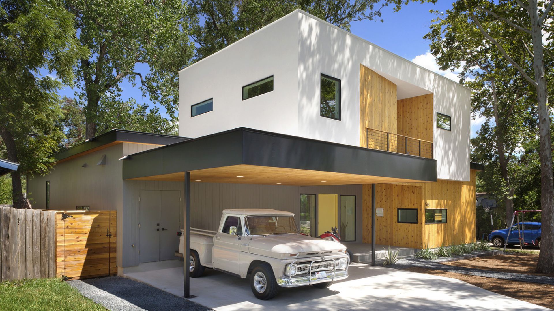 exterior of a modern house with a white and wooden exterior and cars parked in front