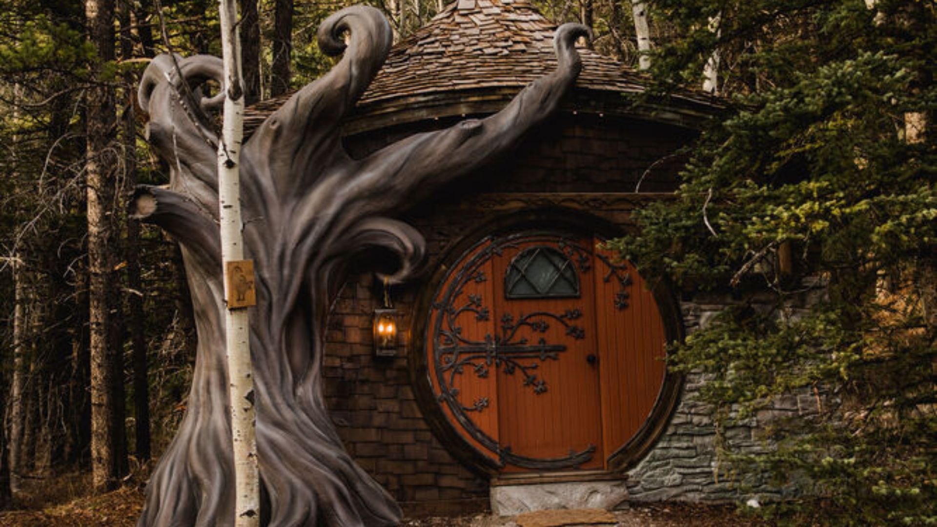 exterior of a cottage with black details on the brown entry doors and a fun tree