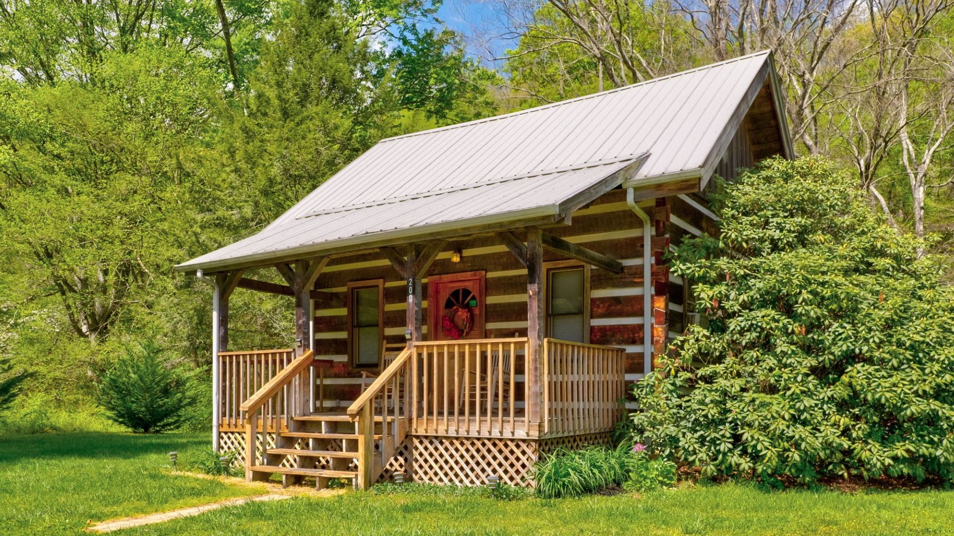 exterior of a tiny log cabin surrounded by greenery