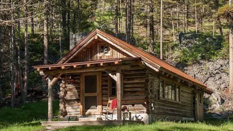 exterior of a log cabin with a small porch and lights on