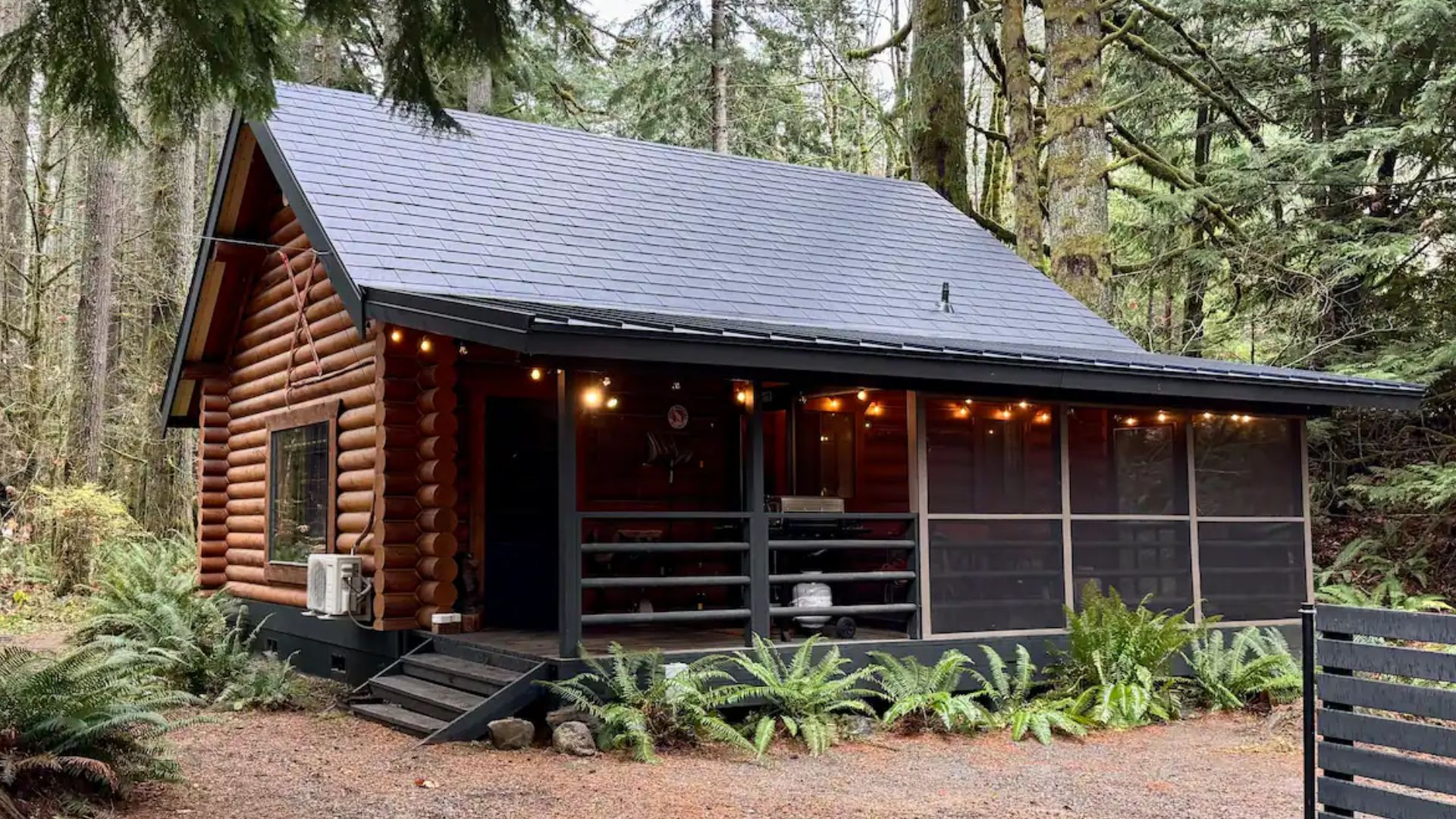 simple wood cabin with a screened porch and green roof