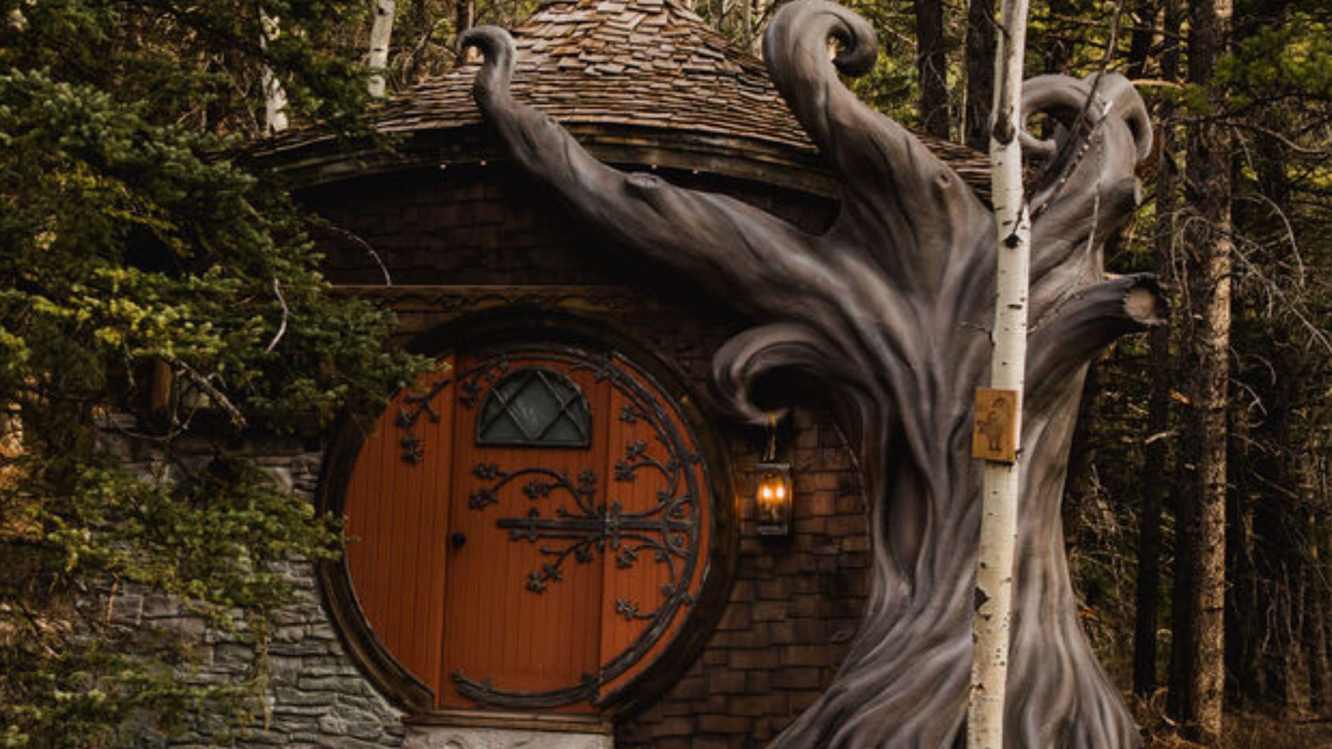 exterior of a cottage with black details on the brown entry doors and a fun tree