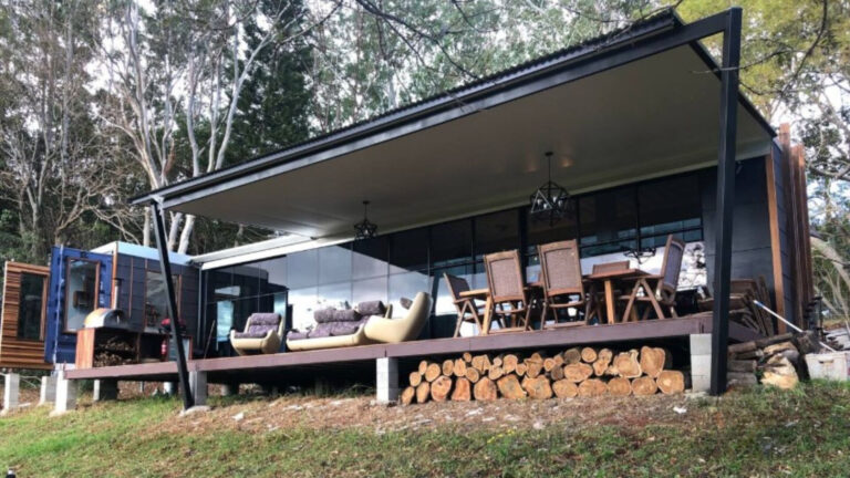 exterior of a container home with a dining table outside and large windows
