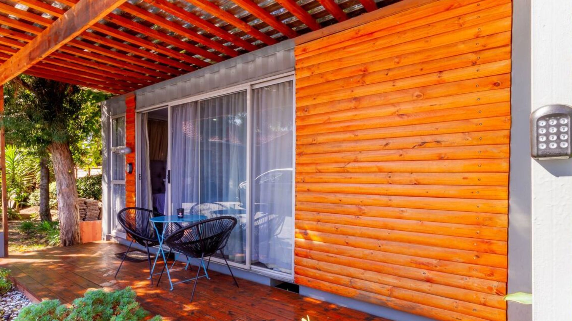 exterior of a container home with brown walls surrounded by greenery