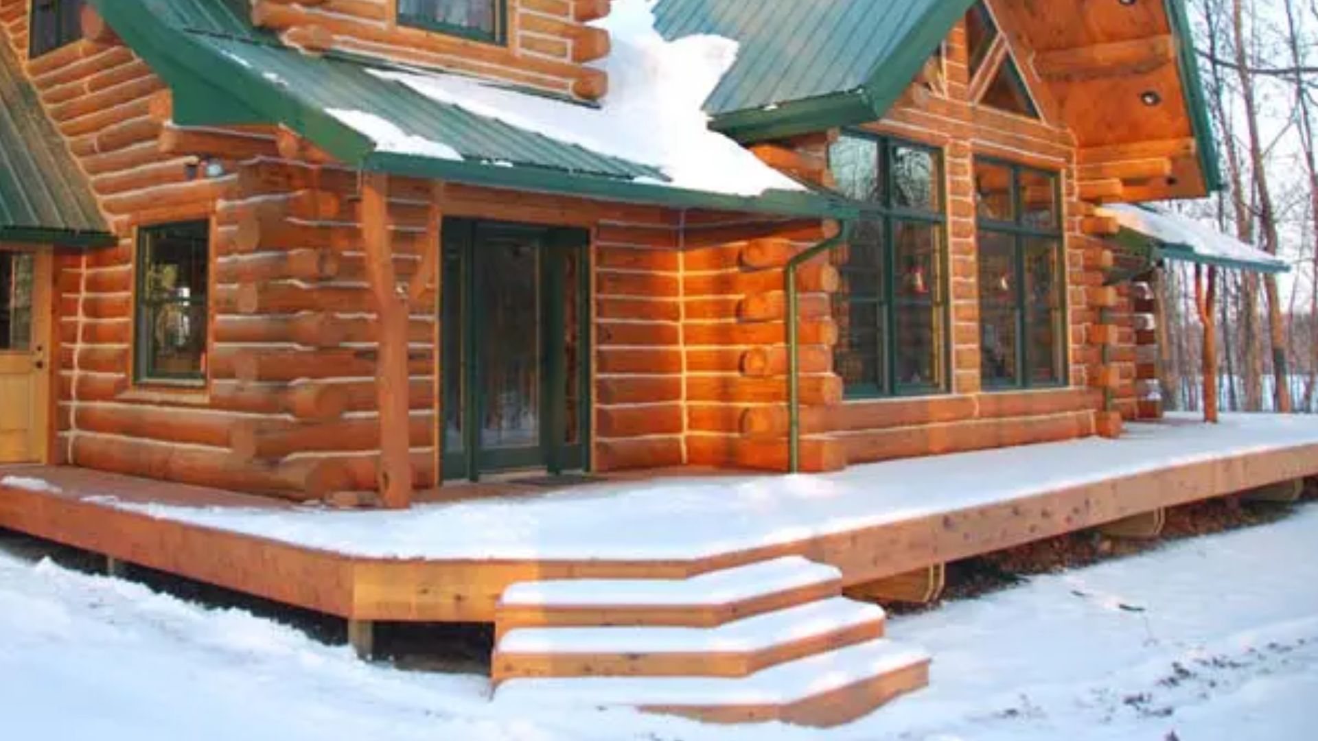 keplar cabin with stained log exterior and green metal roof, double garage adjacent, surrounded by trees