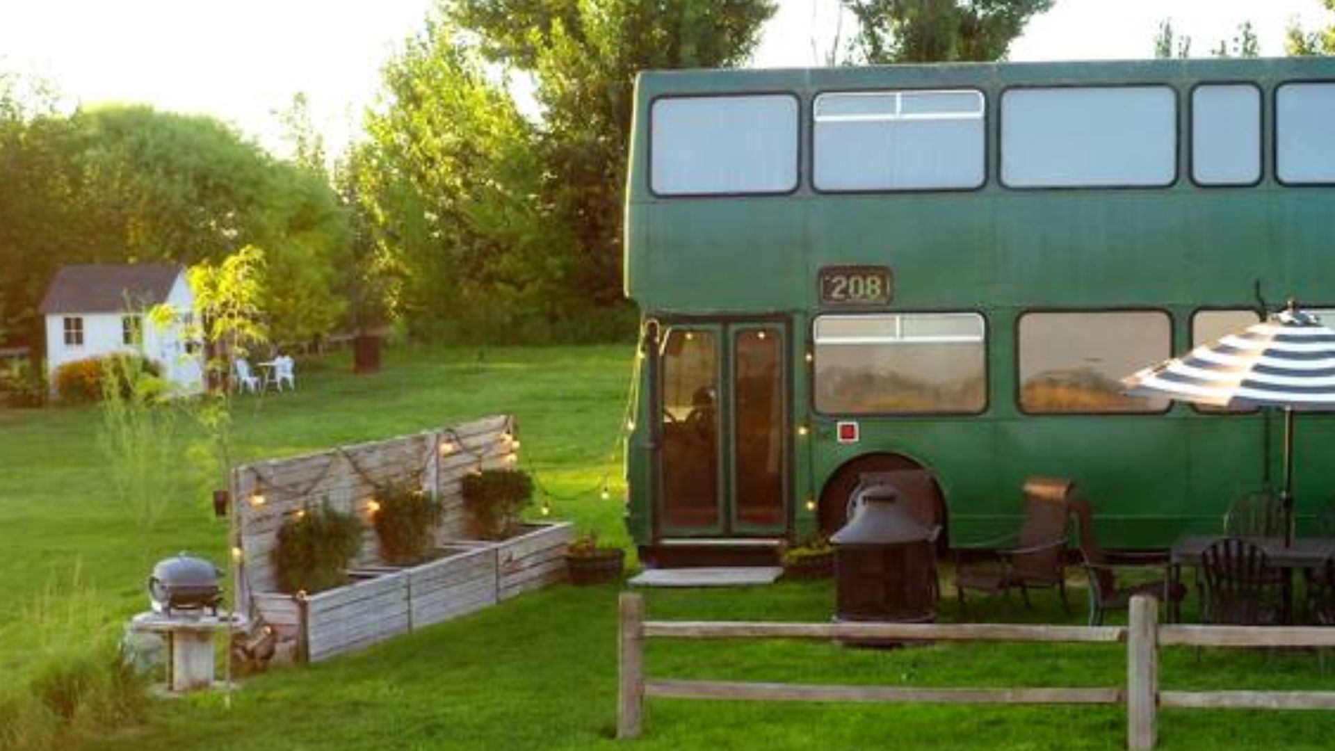 teal green double-decker bus house with a seating area in the front and lots of string lights