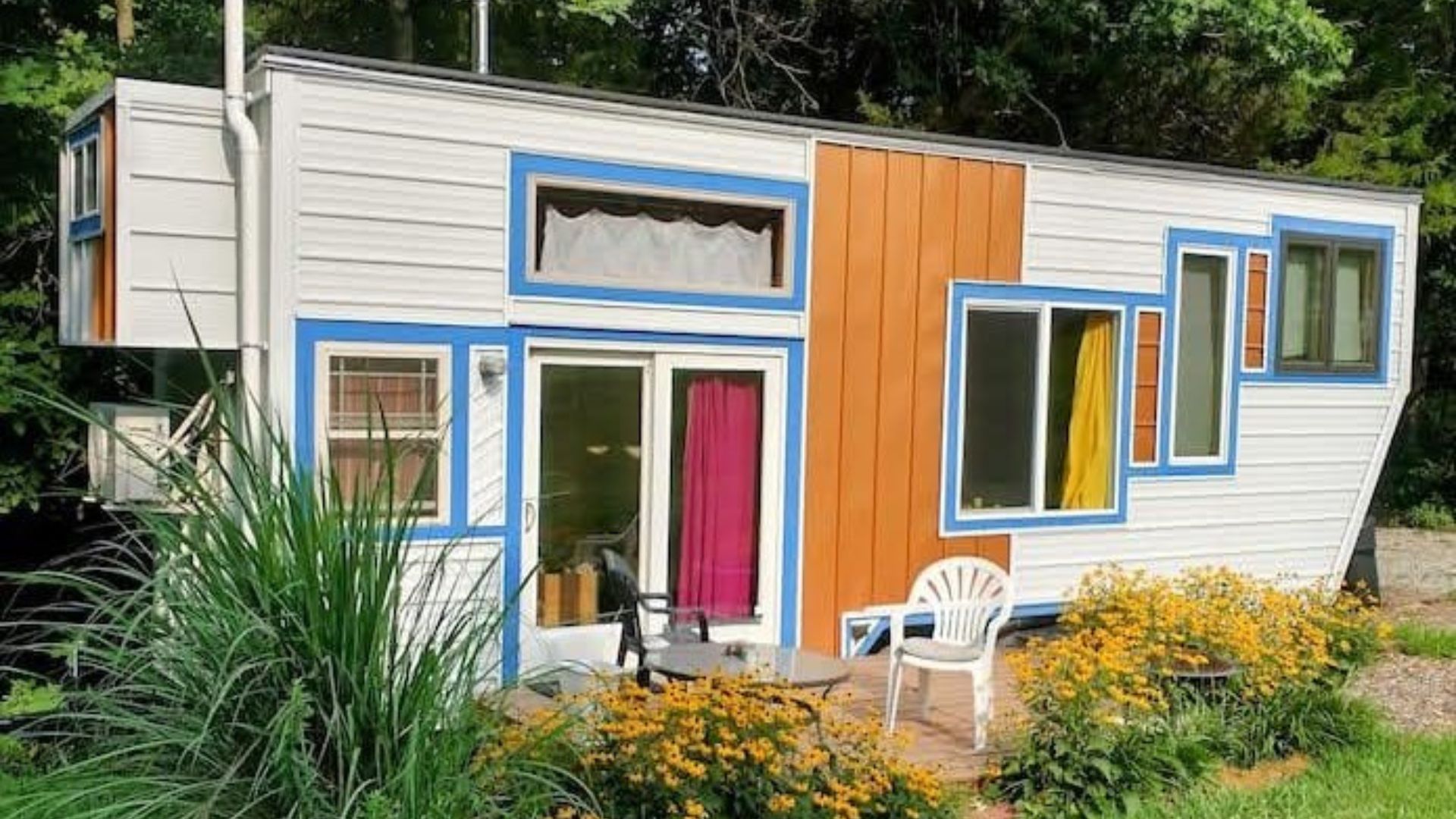 exterior of a tiny home with vibrant colors and a garden with yellow flowers