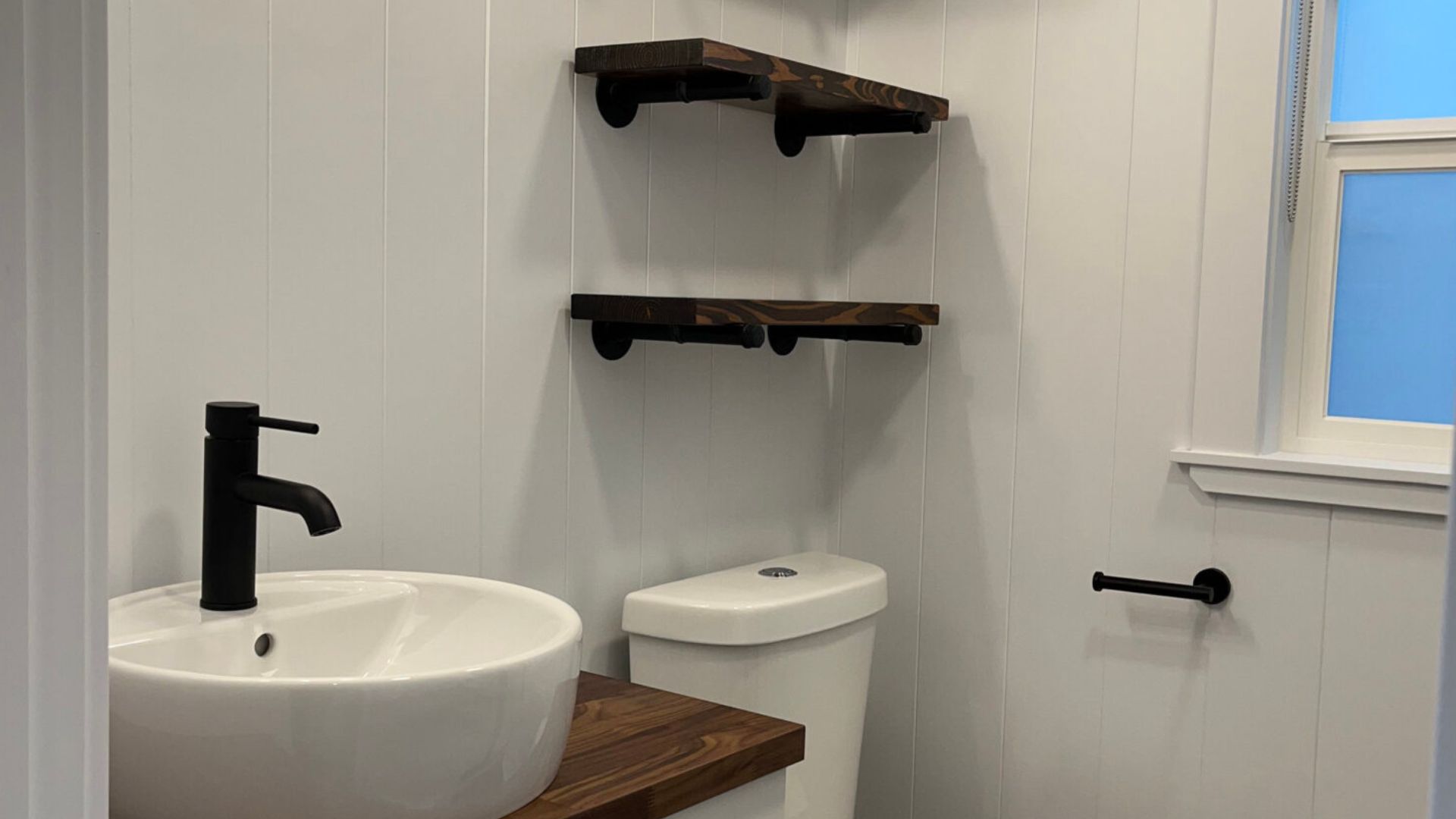 white bathroom with blaack elements and dark wood details