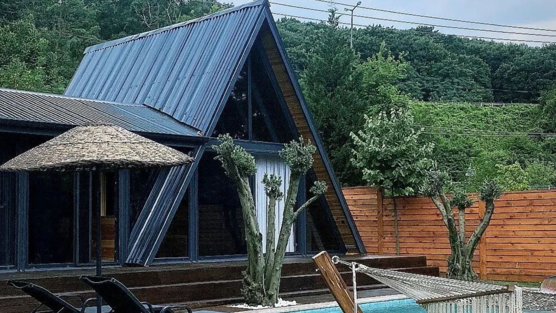 exterior of a tiny house with a-frame roof and a small pool