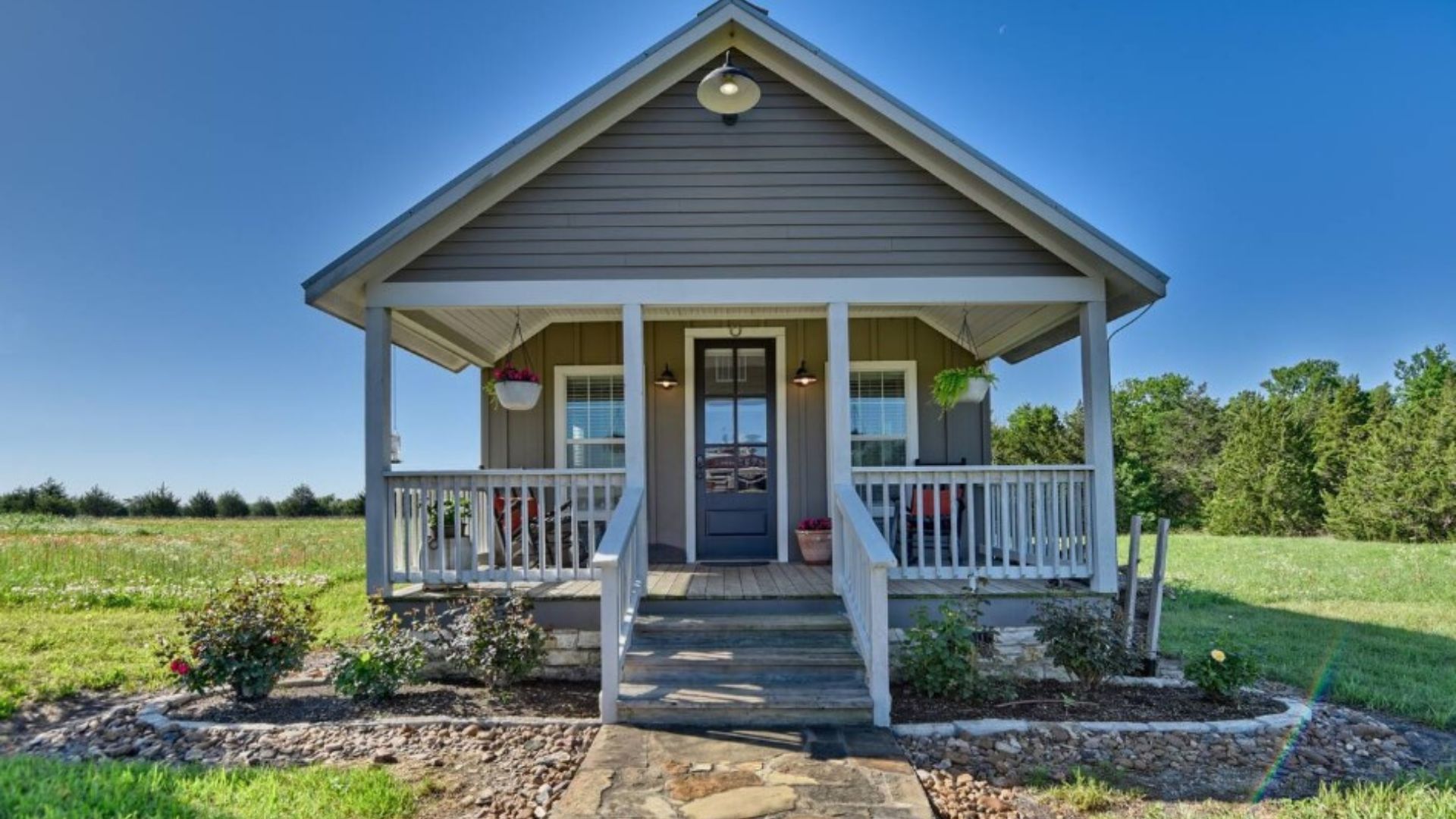 exterior of a tiny home surrounded by big green land