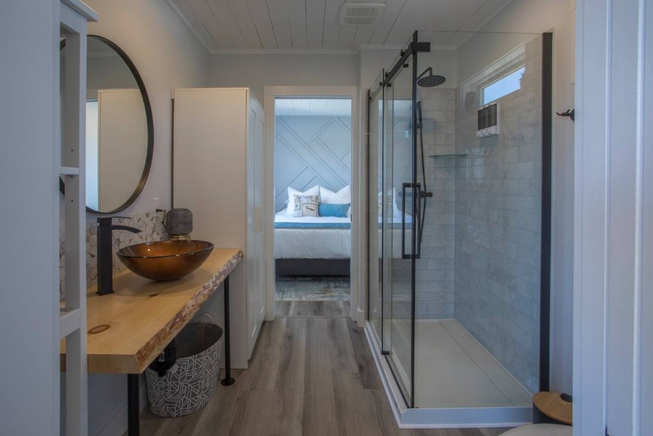 bathroom with a glass shower, wooden countertop, round mirror