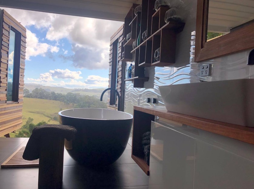 bathroom with a black tub, brown shelves