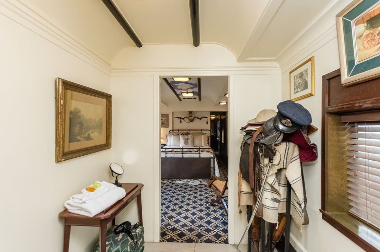 bathroom with a clothing rack, shelf with towels, old framed photos