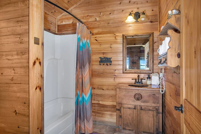 bathroom with wooden walls, shower, wooden cabinet with a mirror above