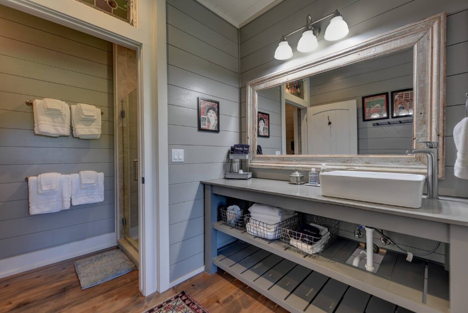 bathroom with an open gray cabinet and a big mirror, white sink, glass shower