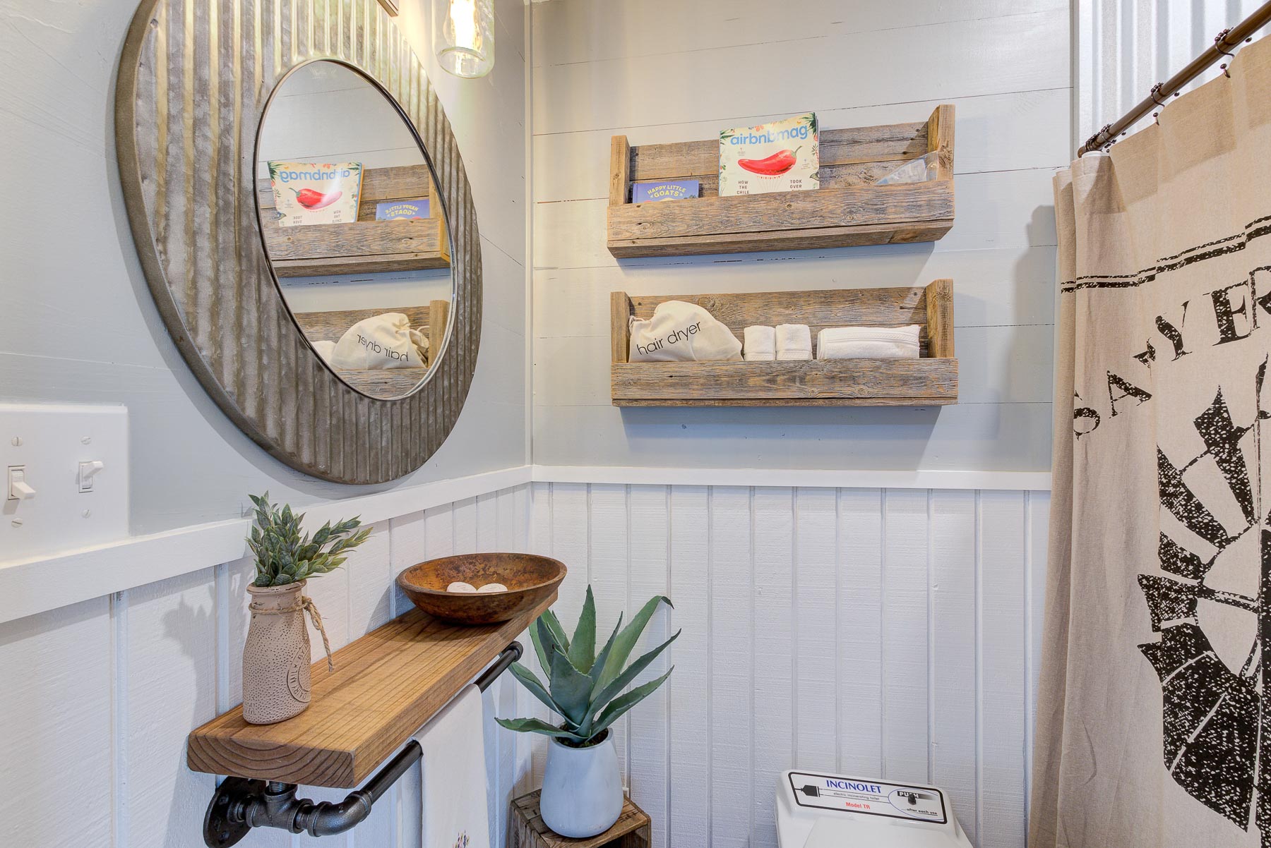 bathroom with wooden shelves, round mirror