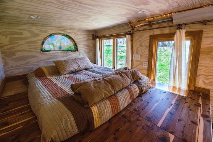 bedroom with wooden walls and flooring, bed with brown bed sheets