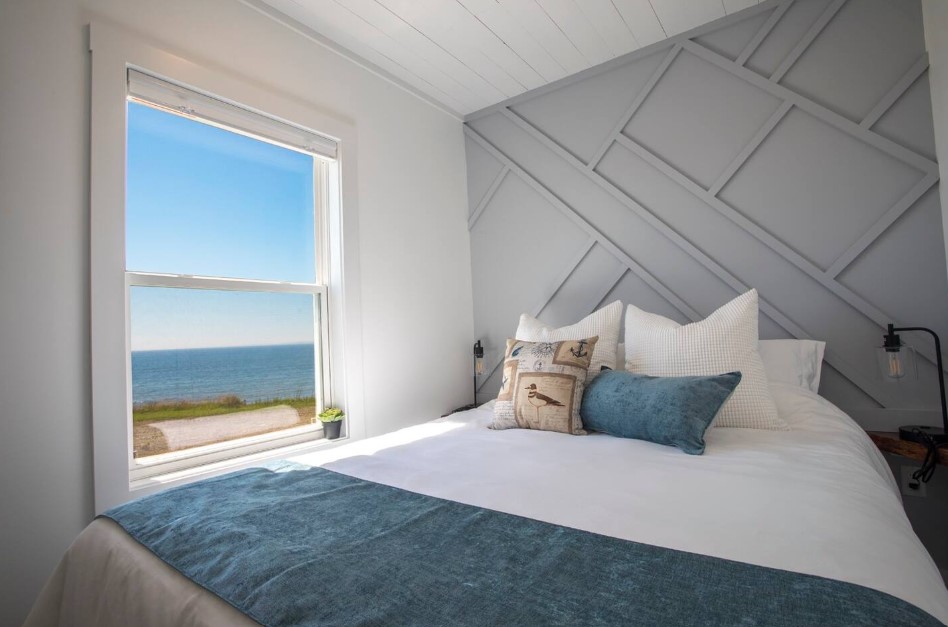 bedroom with one gray wall, bed, a window with an ocean view