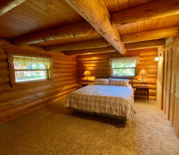 bedroom with one bad, two windows, wooden beams